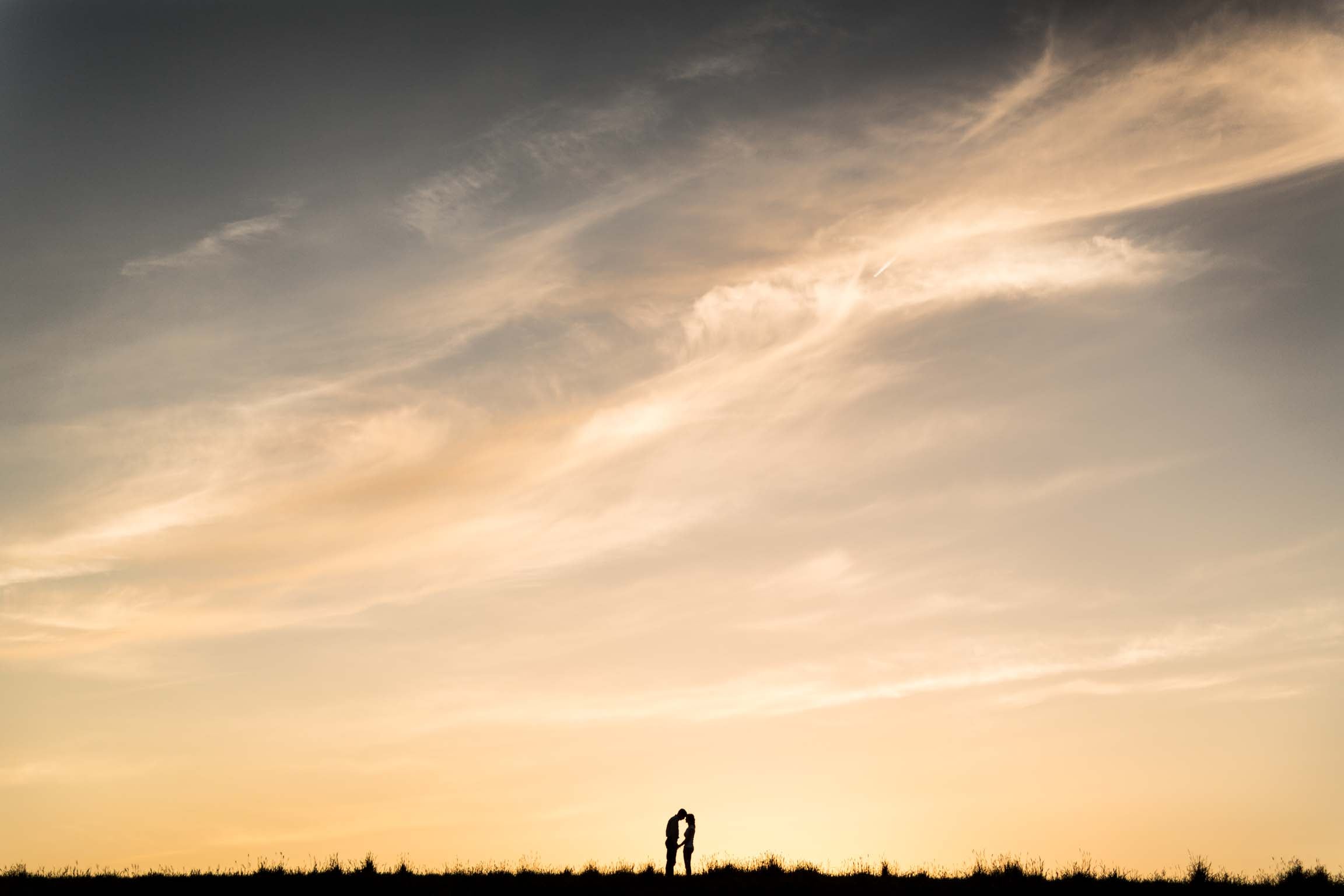 Silhouette of a couple facing each other with the background of a sunset sky 