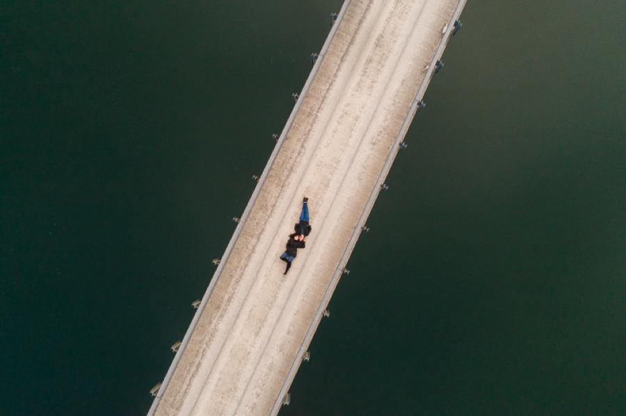 Drone shot of a couple lying over a bridge