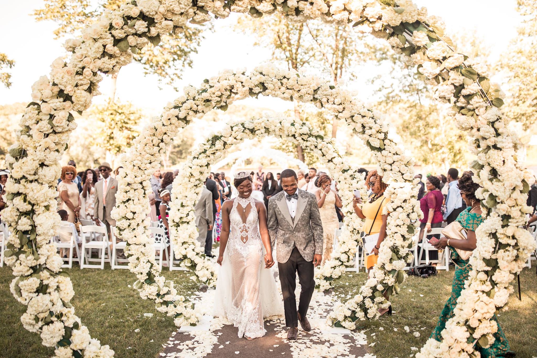 A couple of color walking down the aisle decorated with floral arrangements  