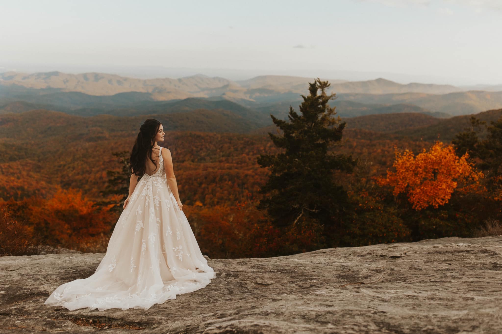 a bride standing at the edge of a cliff in her bridal attire