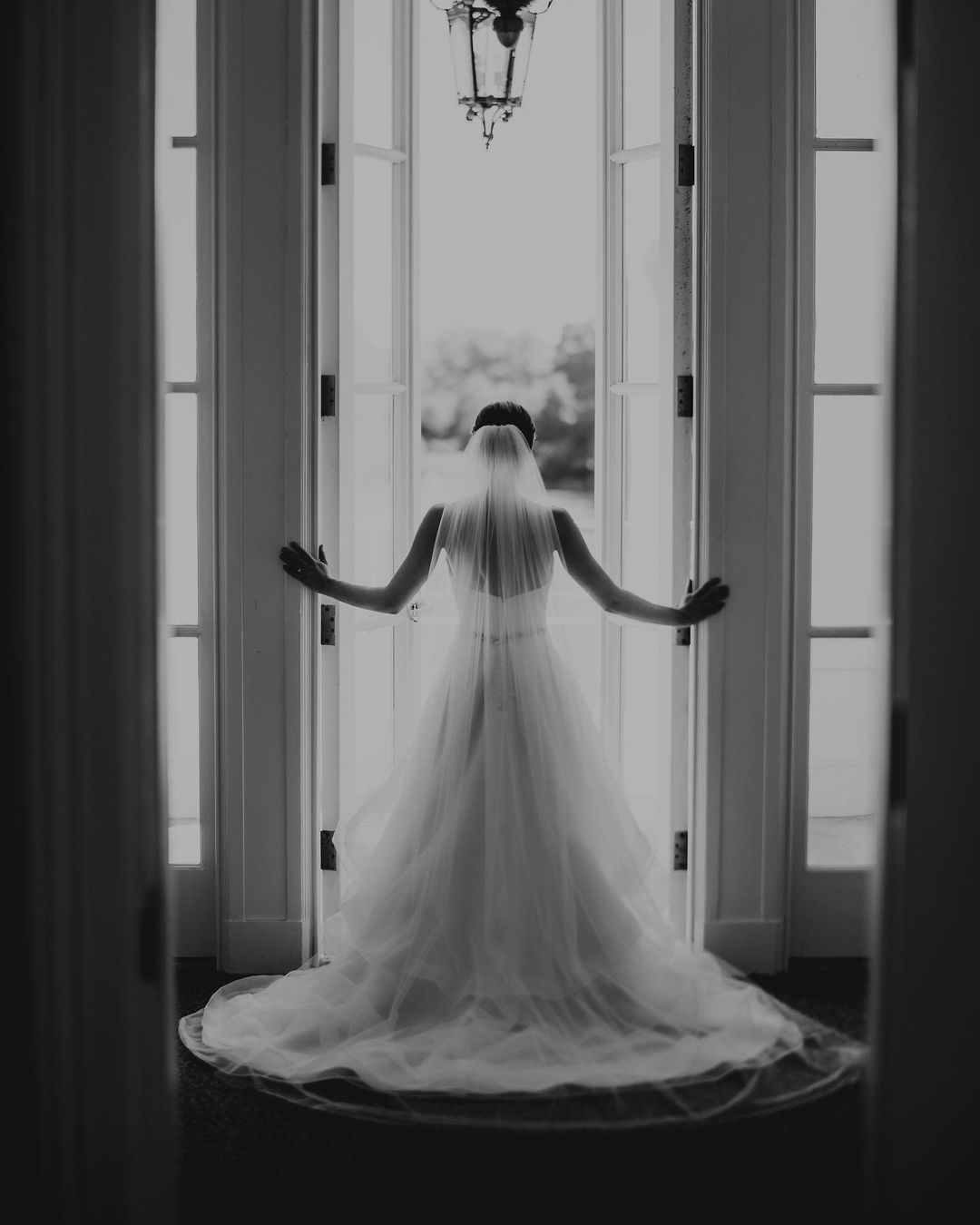 a bride standing in her wedding dress in front of the door and opening it