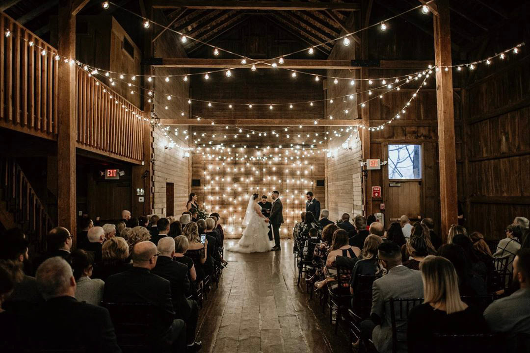 a wedding couple is standing holding hands at a beautifully lit wedding ceremony venue