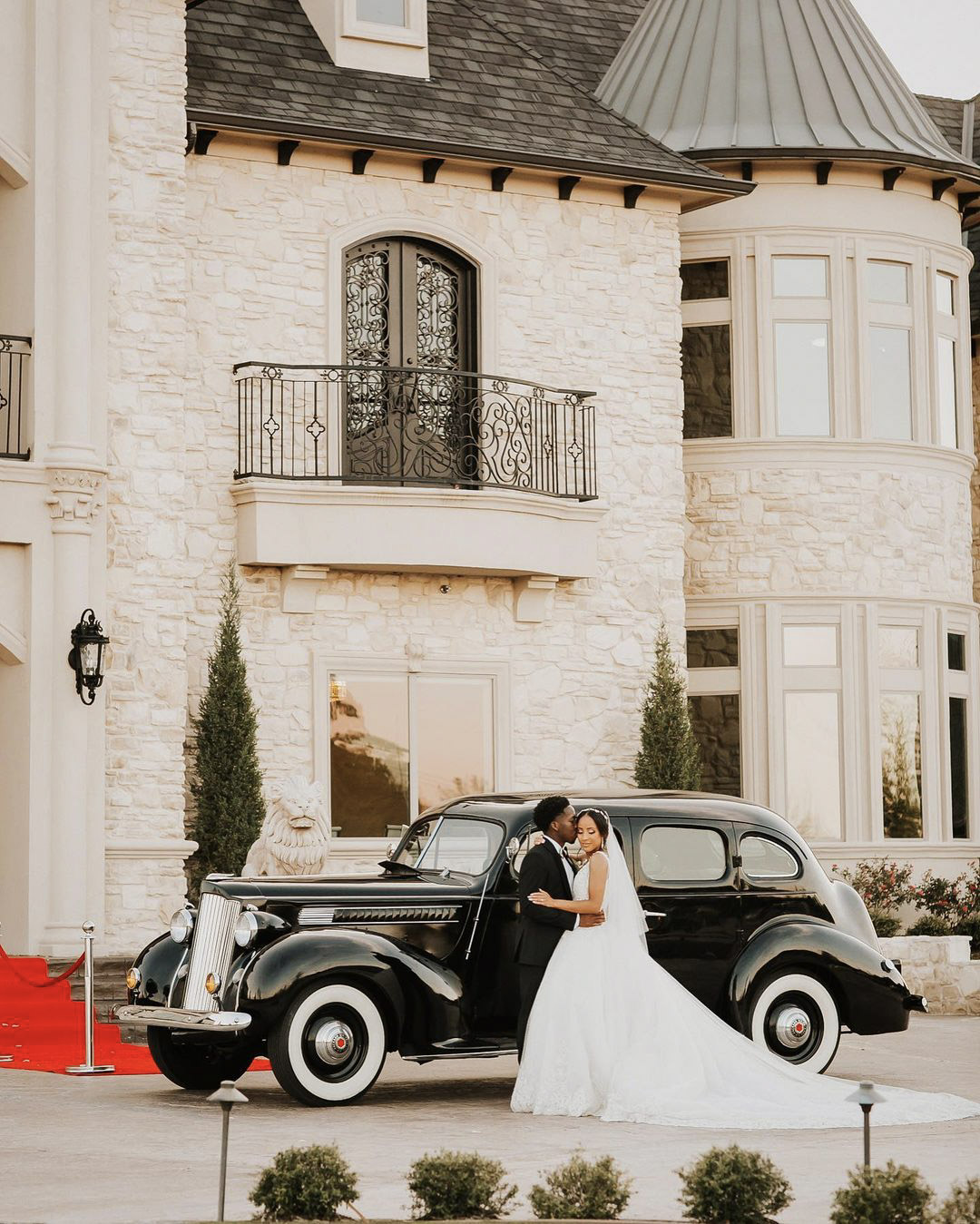 a wedding couple standing in front of a majestic mansion