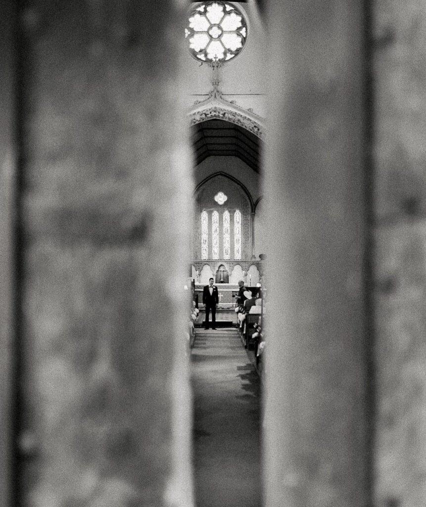 the groom waiting for the bride at the altar viewed through a small gap