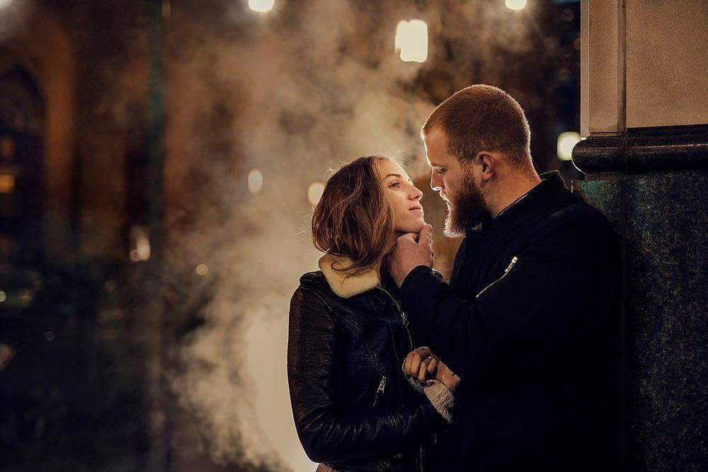 A portrait of a couple standing at a street side looking at each other