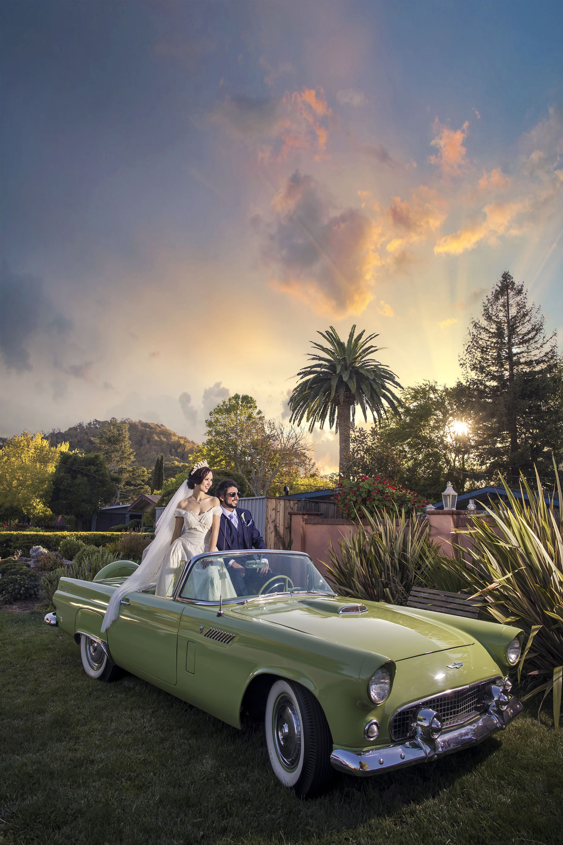 a bride and a groom sitting on a car