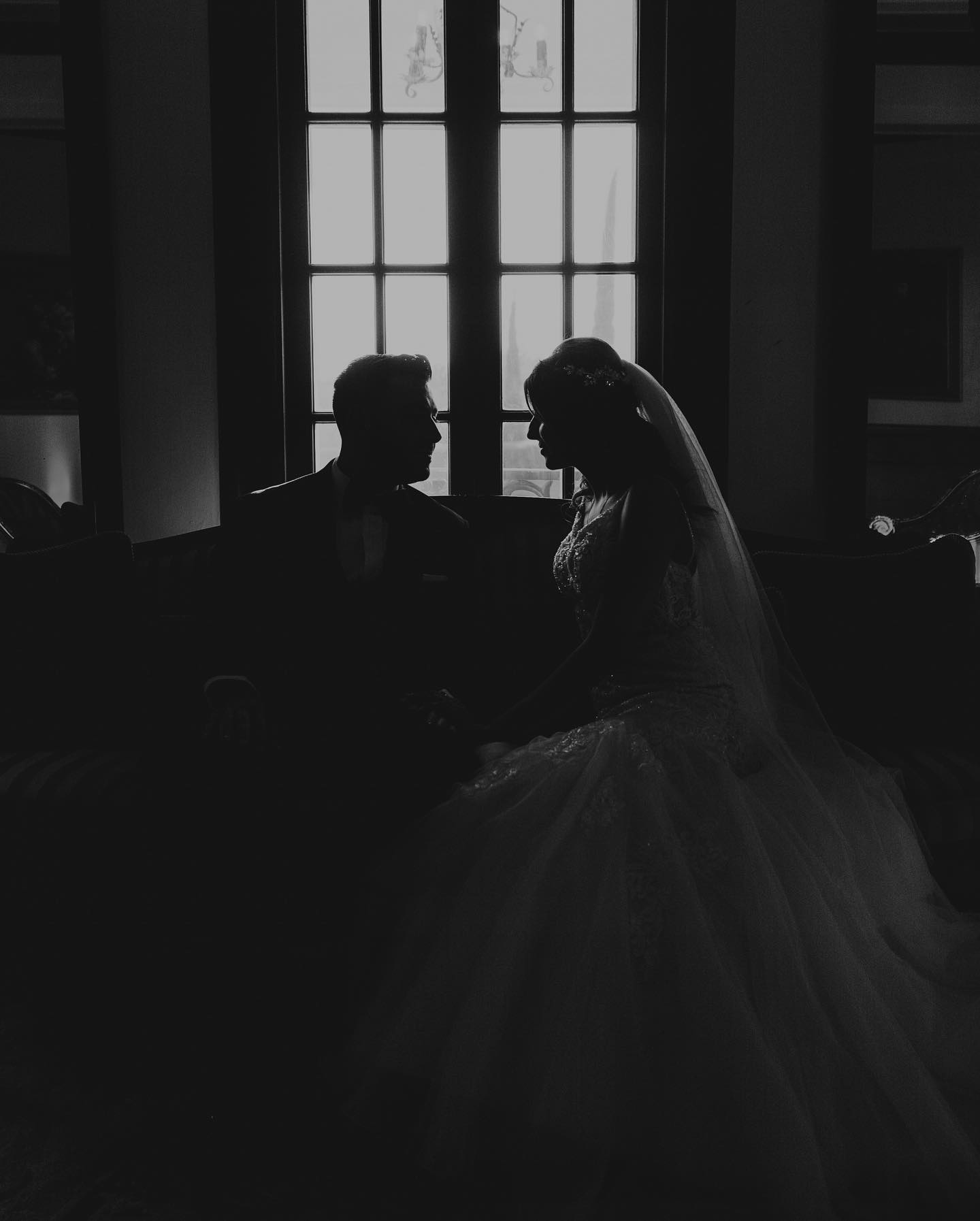 Black and white silhouette of a couple sitting on a couch facing each other 