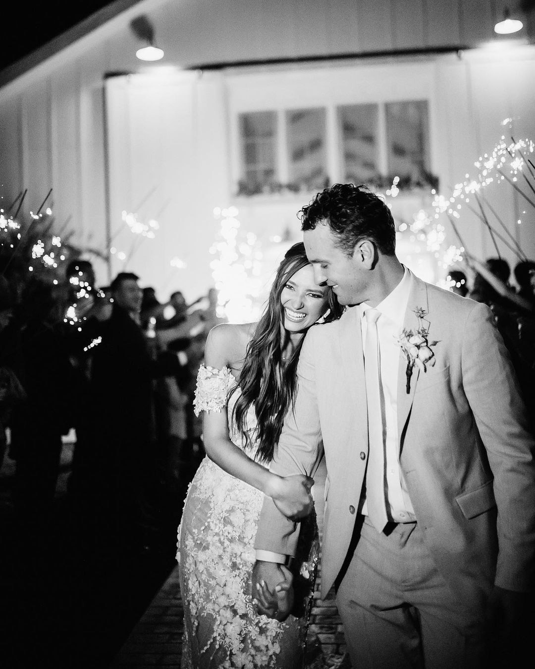 the bride holding on to the groom's arm and laughing after a sparkler wedding exit