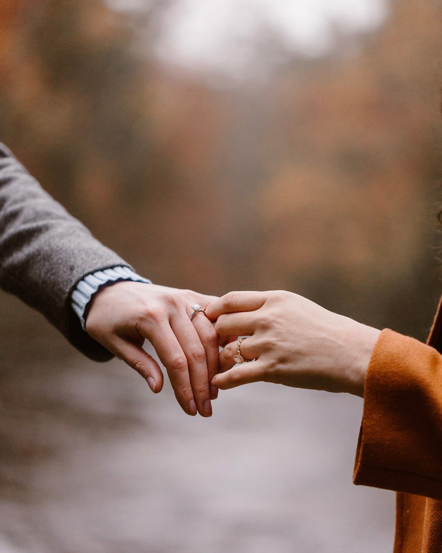 an engaged couple holding hands with their engagement rings showing