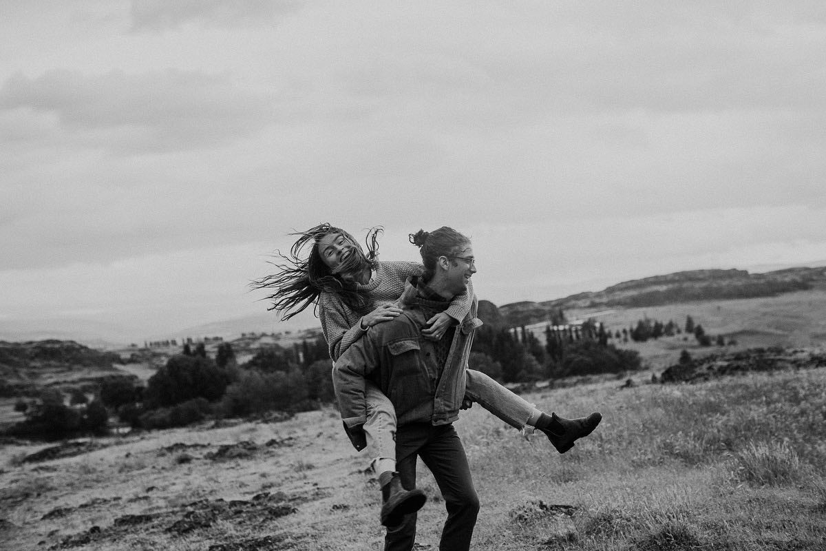 an engaged couple where the groom is giving the bride a piggyback ride