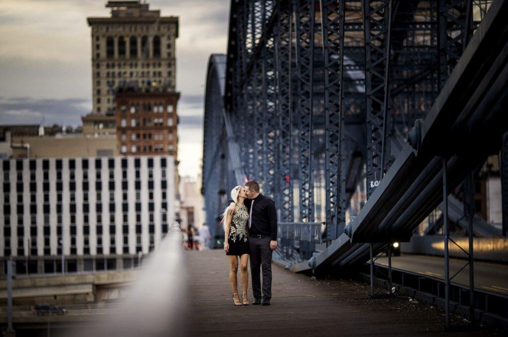 a couple kissing while walking by the side of a bridge