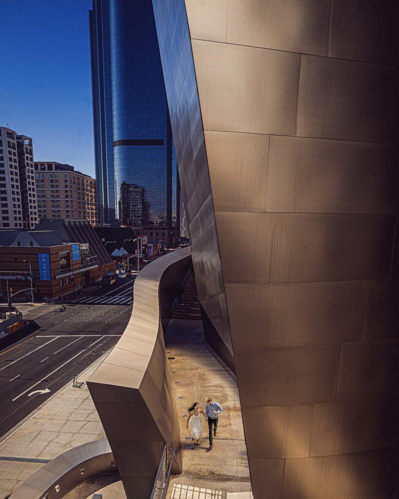 a couple running holding hands beside a beautiful building