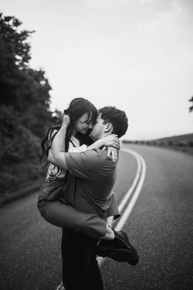 an engaged couple kissing while the groom picked up the bride