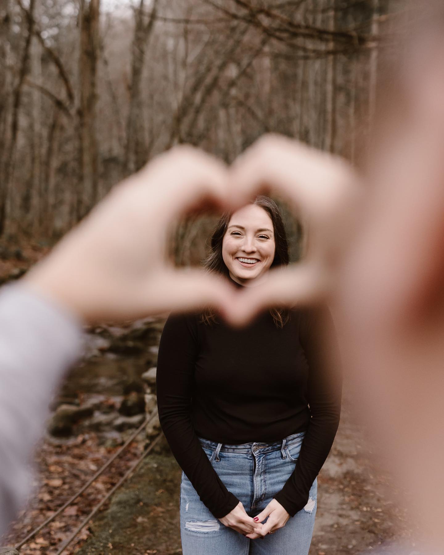 a picture of the bride through a heart shape made by the groom's hands