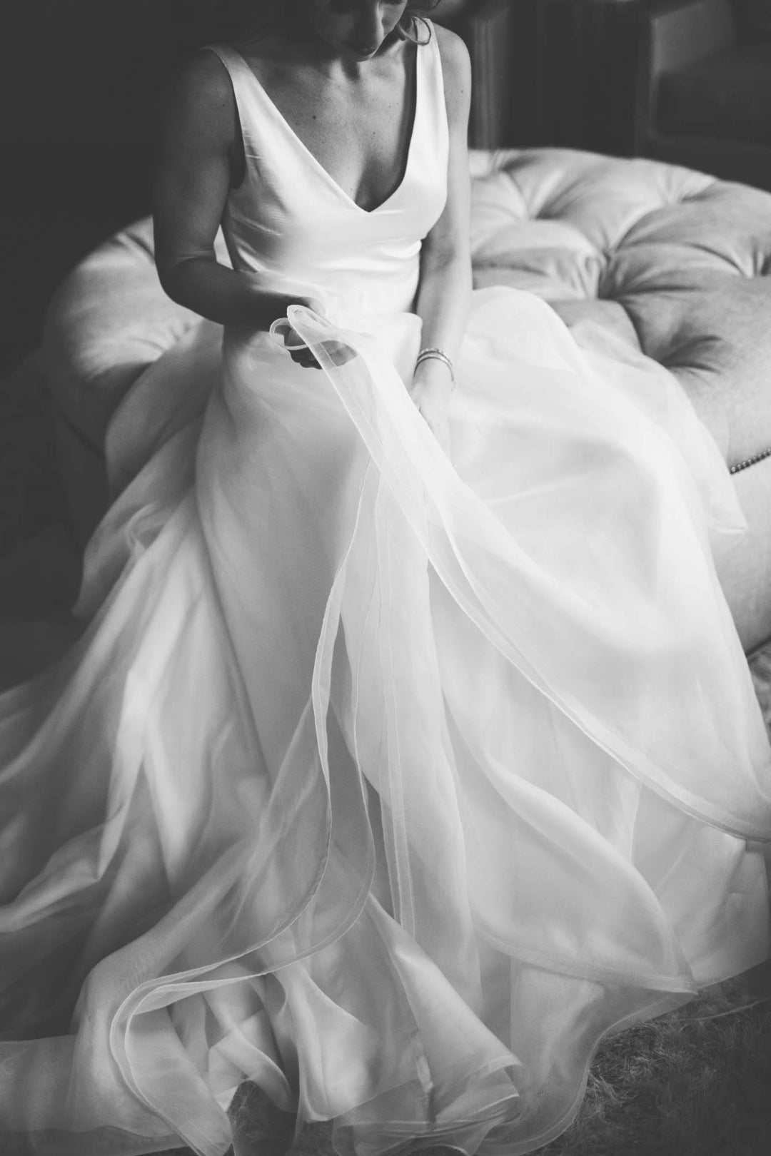 Black and white photo of a bride holding the skirt of her bridal dress