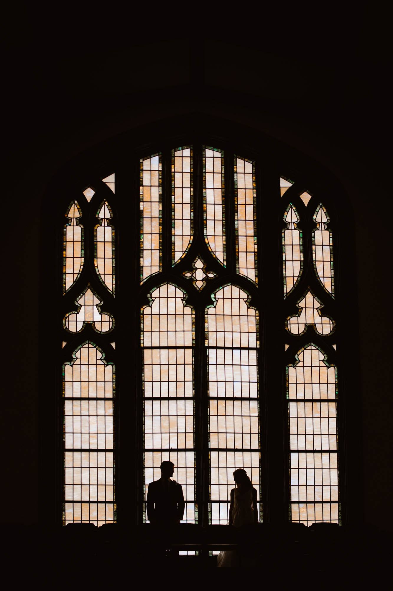 Silhouette of a bride and groom standing in front of a window in a church