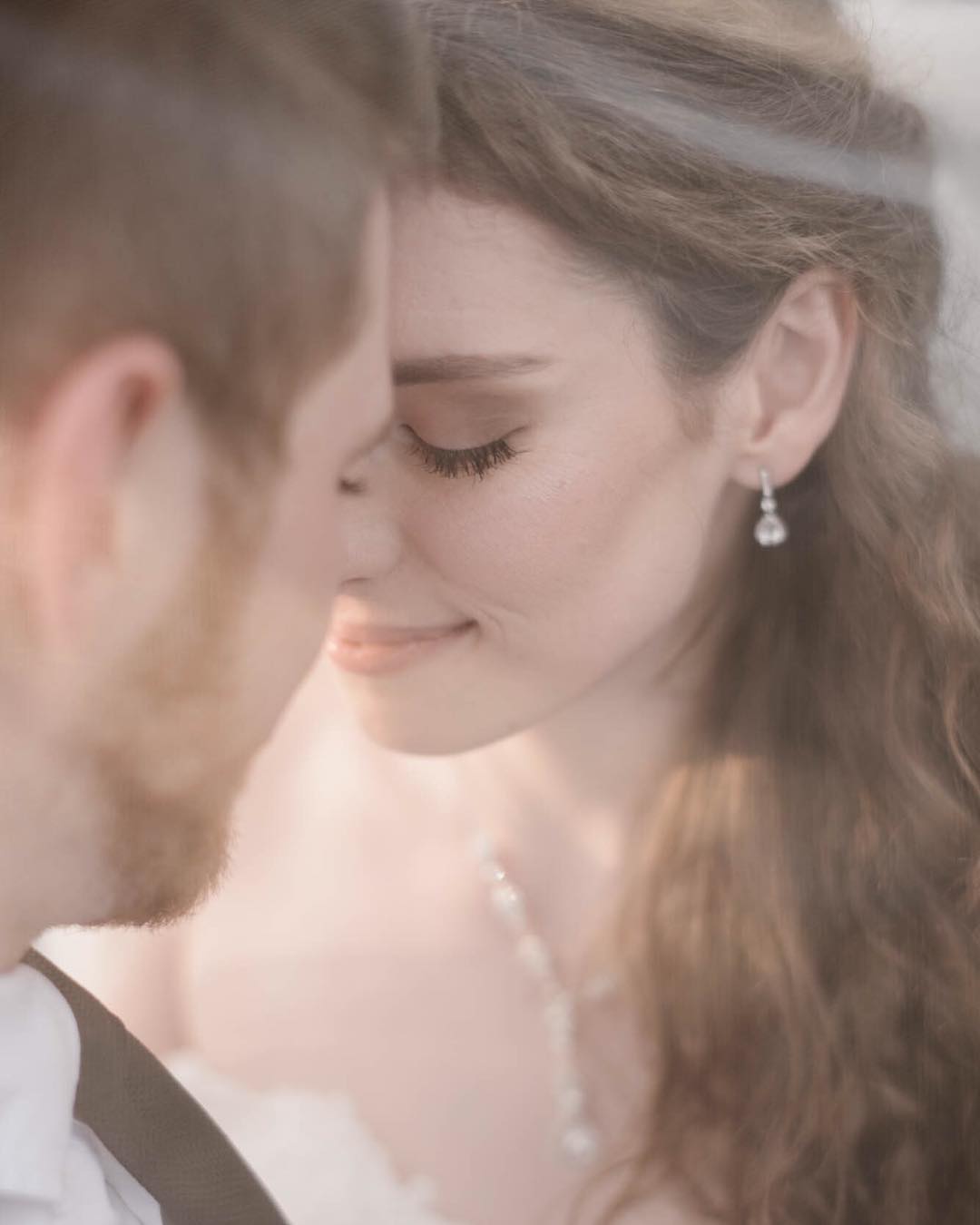 A close up portrait of a bride and groom smiling and leaning their foreheads on each other