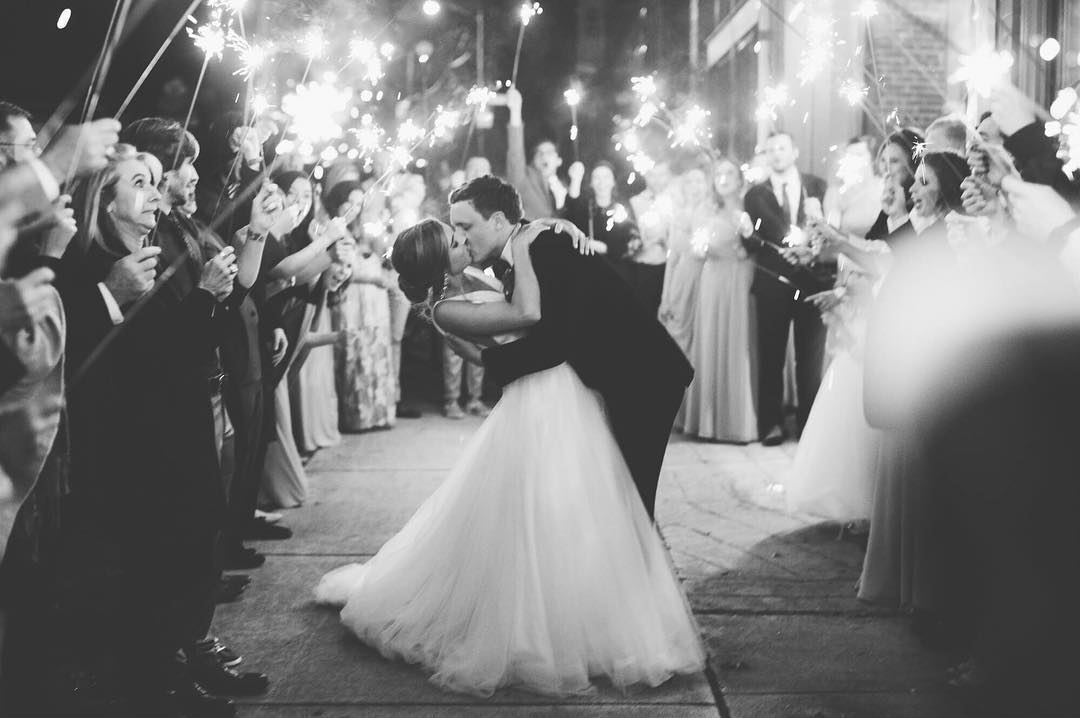 A bride and groom kissing during the exit at the wedding reception as the guest surround them with sparklers