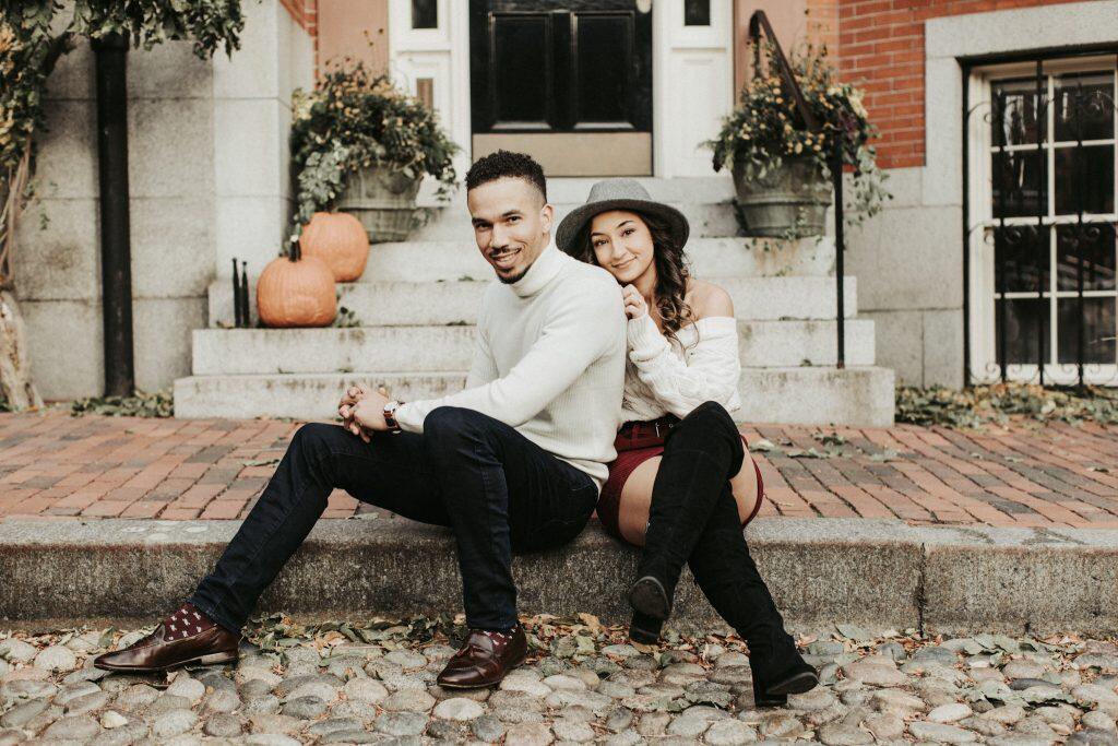 a couple sitting on the pavement with the bride leaning on the groom's shoulder