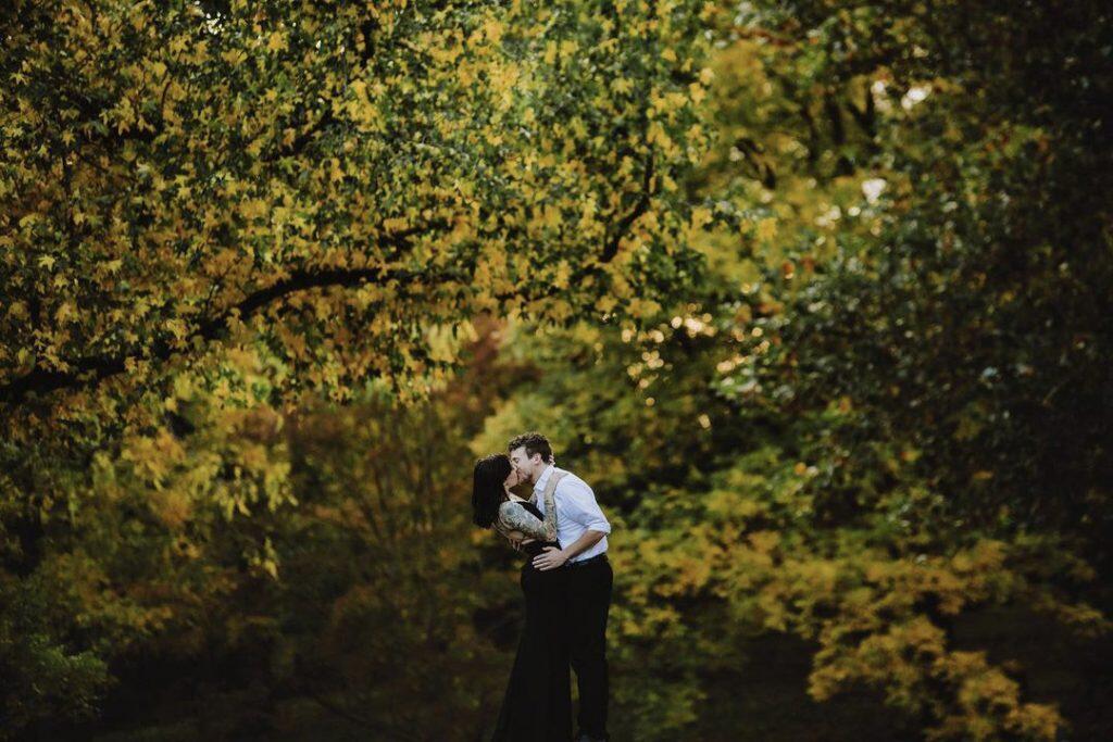 a couple kissing embracing each other amidst foliage