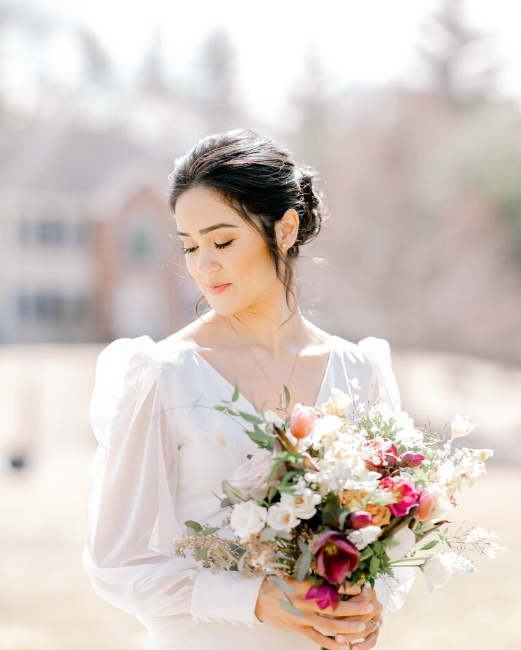 a wedding bride posing in her wedding attire with the wedding bouquet