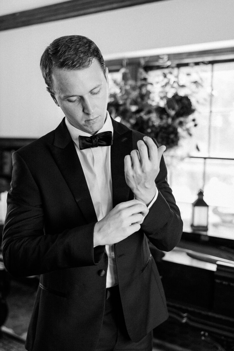 a wedding groom in his wedding suit adjusting the cuffs