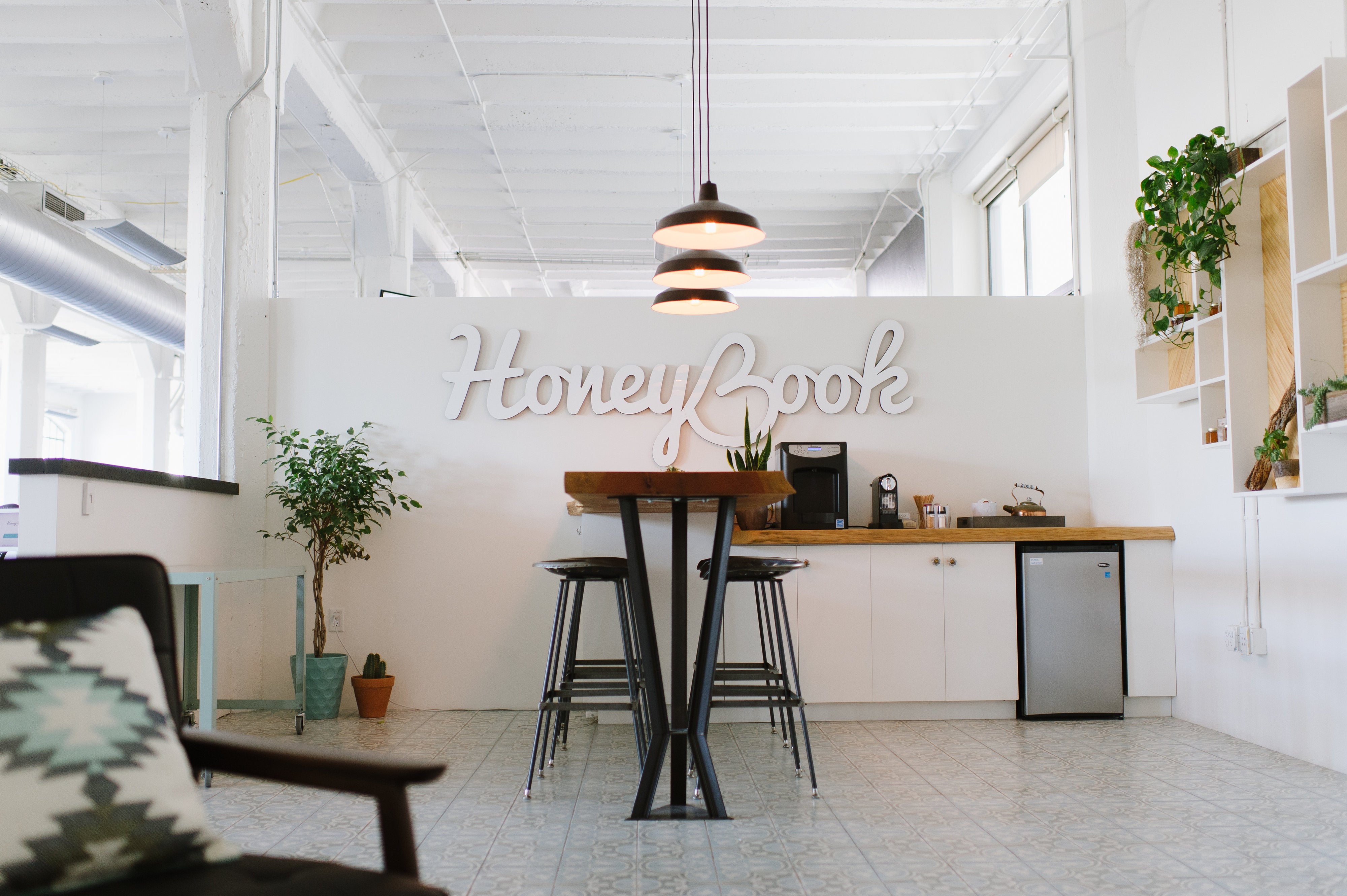 A client management software HoneyBook logo engraved on a white wall