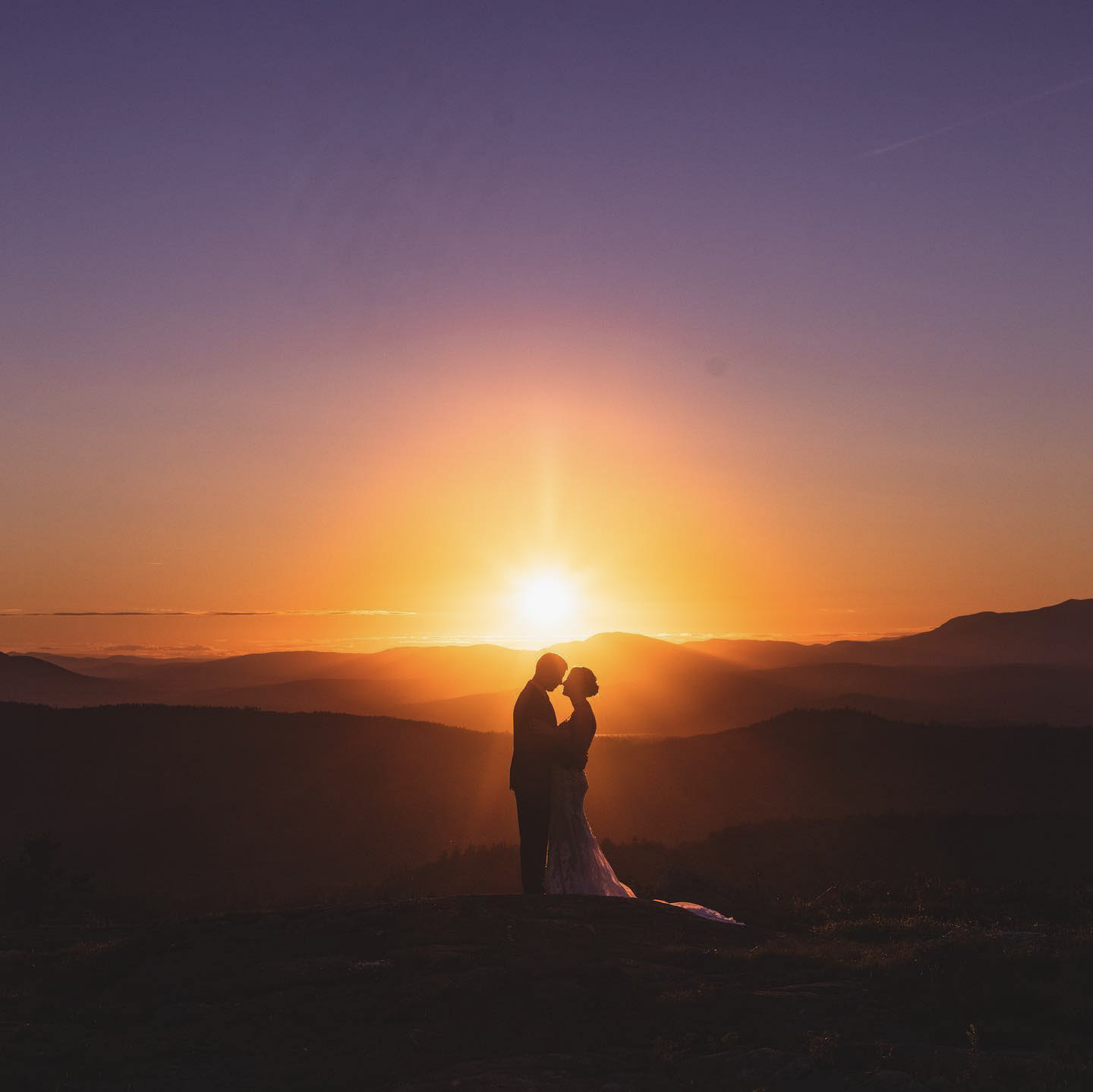 a silhouette of a wedding couple standing with beautiful hilly range behind them