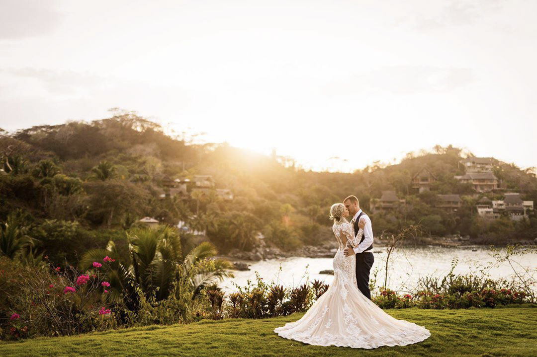 a couple kissing while the sun is setting behind some hills