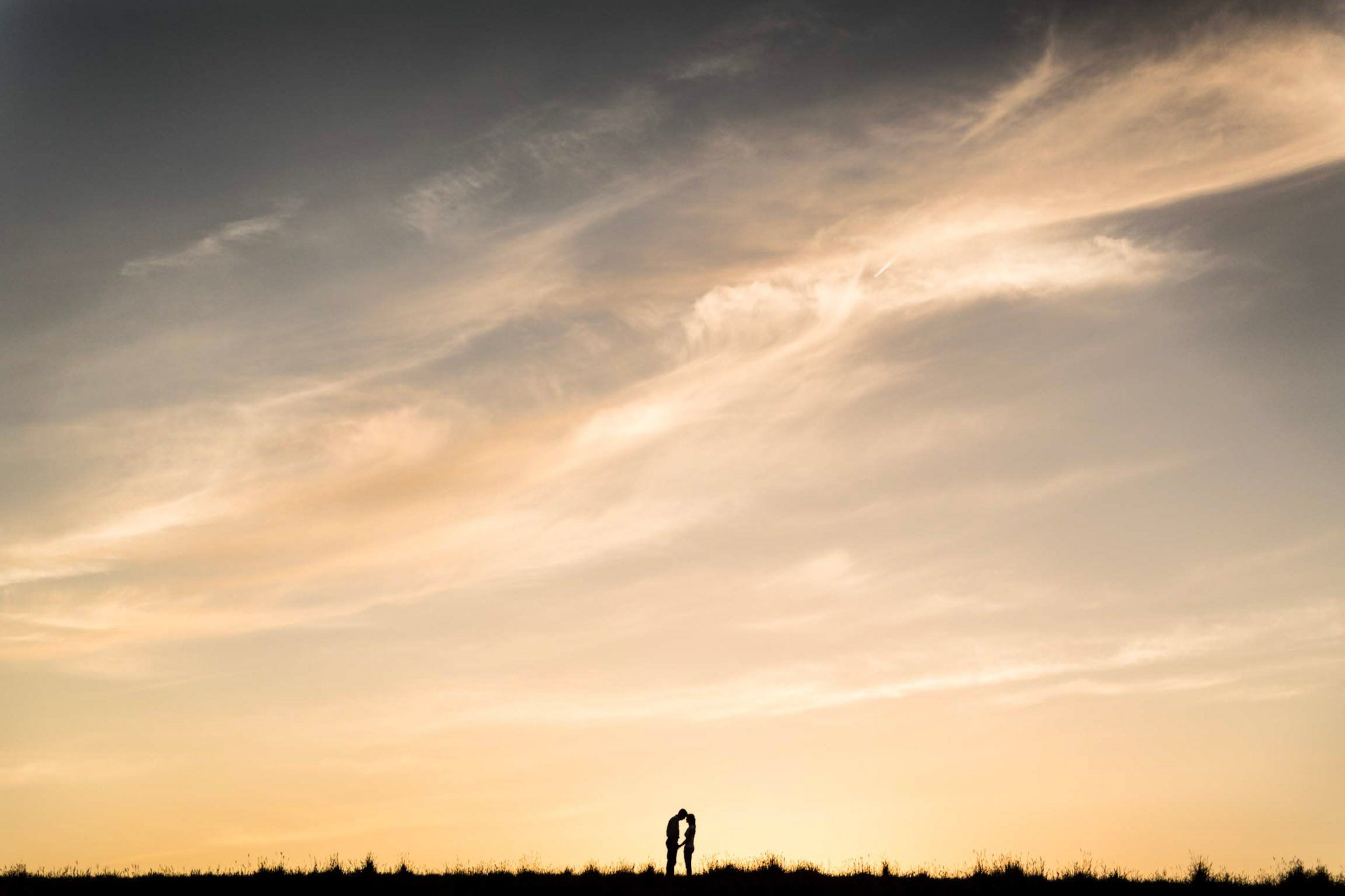 a couple standing holding hands with beautiful open skies over them