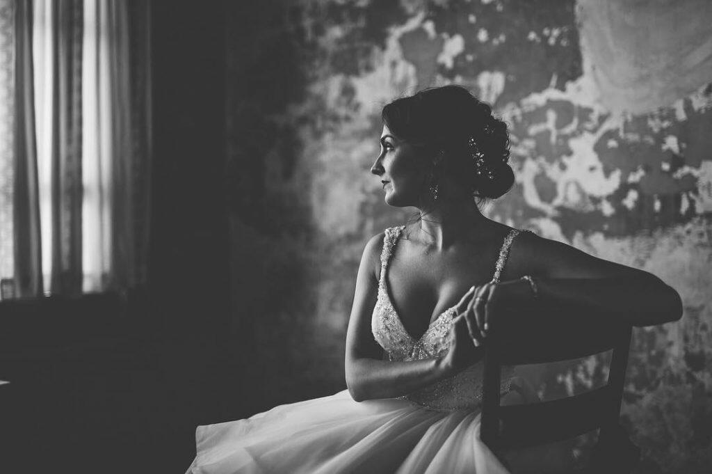 a bride sitting in her wedding attire staring at the window