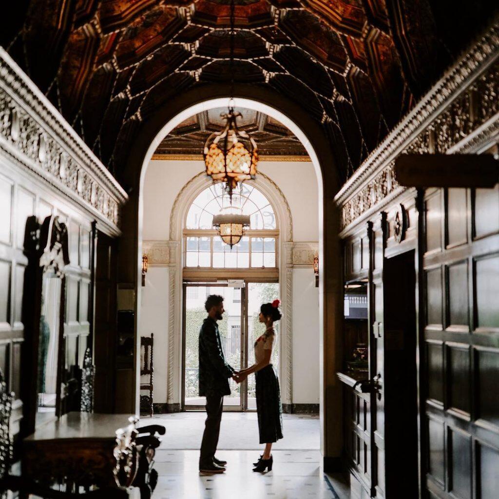 a wedding couple standing in the hallway holding each other's hands