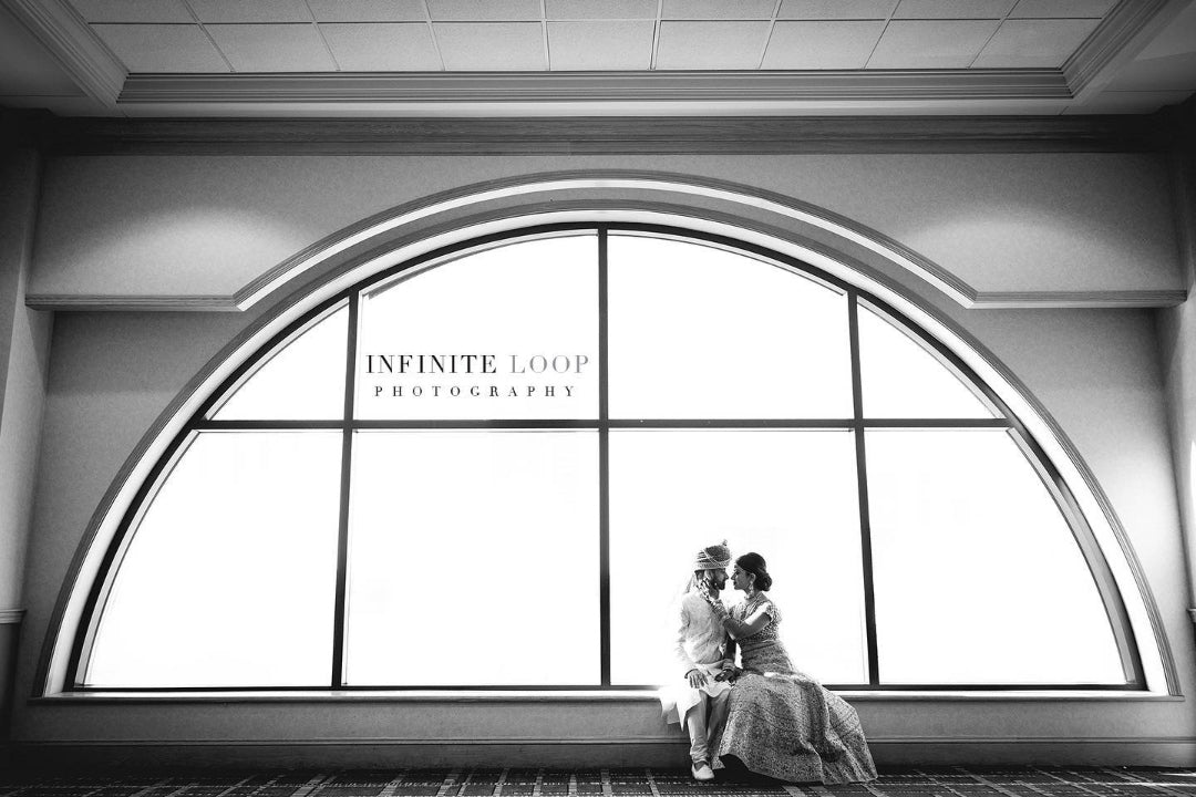 Black and white photo of a bride and groom dressed in a traditional outfit posing