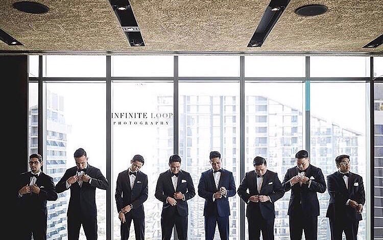 A group of groomsmen standing in front of a window