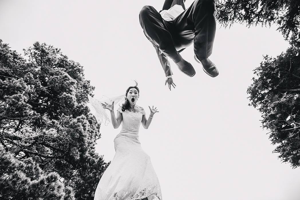 Bride and groom striking a pose mid air  creating a unique wedding photo