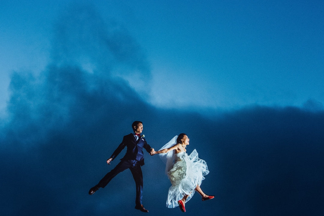 Bride and groom doing a jump shot while holding each other's hand