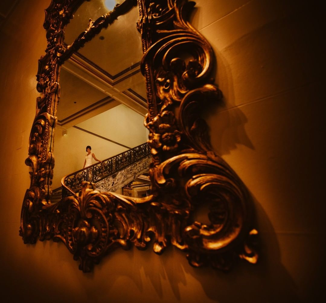 The action of a bride walking down the stairs captured through a mirror frame