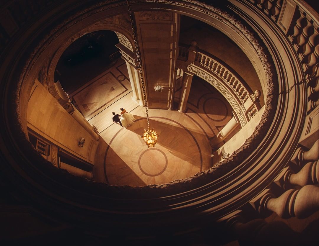 High-angle view of a bride and groom walking towards the doorway of a spiral auditorium