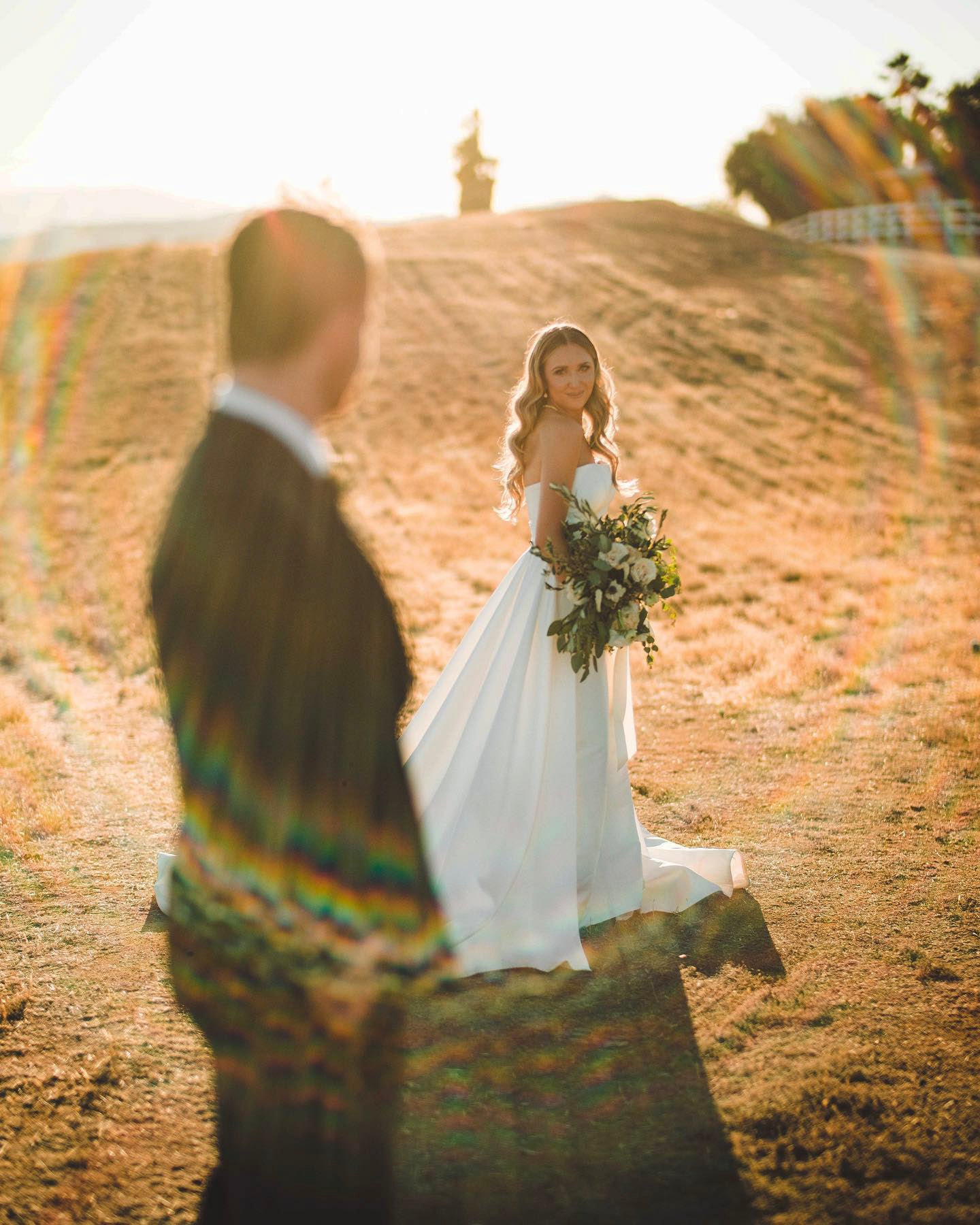 a couple looking at each other standing on a large empty field 