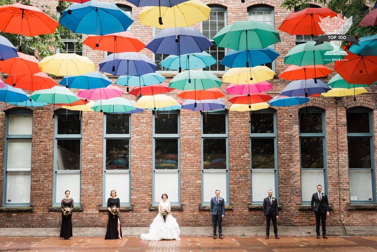 bridal party photos with party standing under color umbrellas