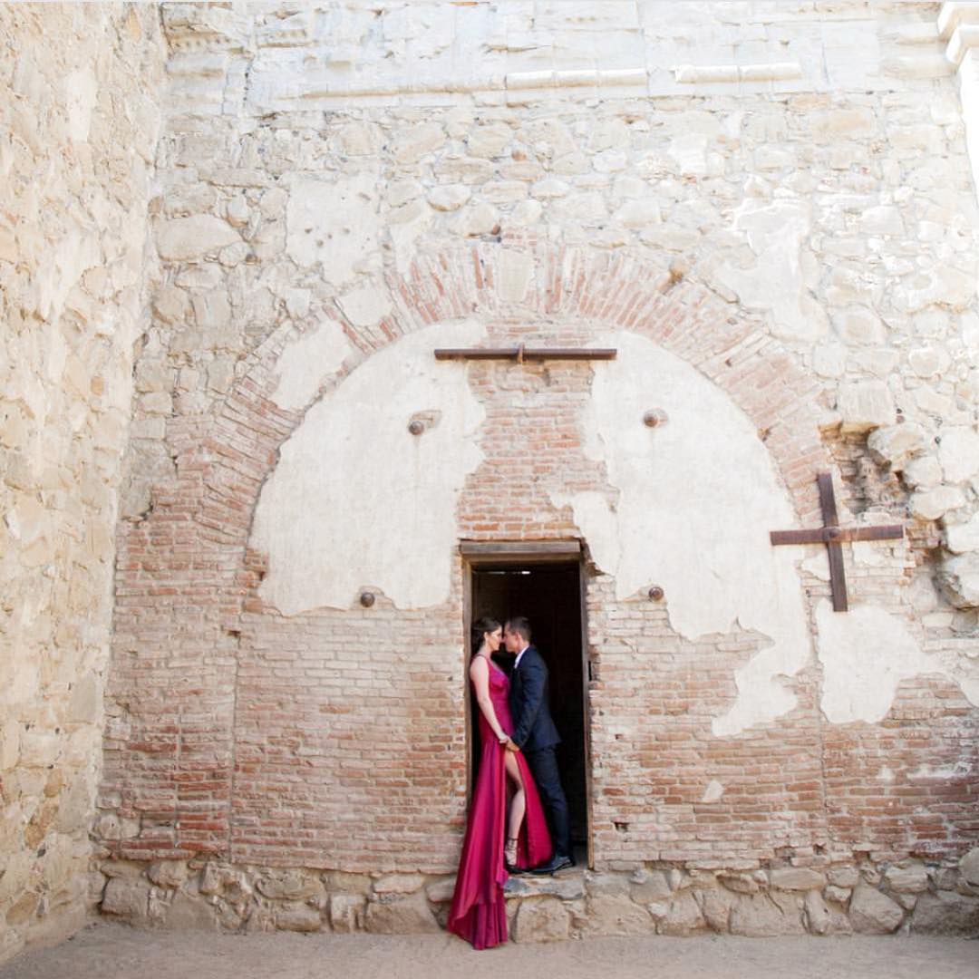 a couple posing intimately on the doorway of a stone structure