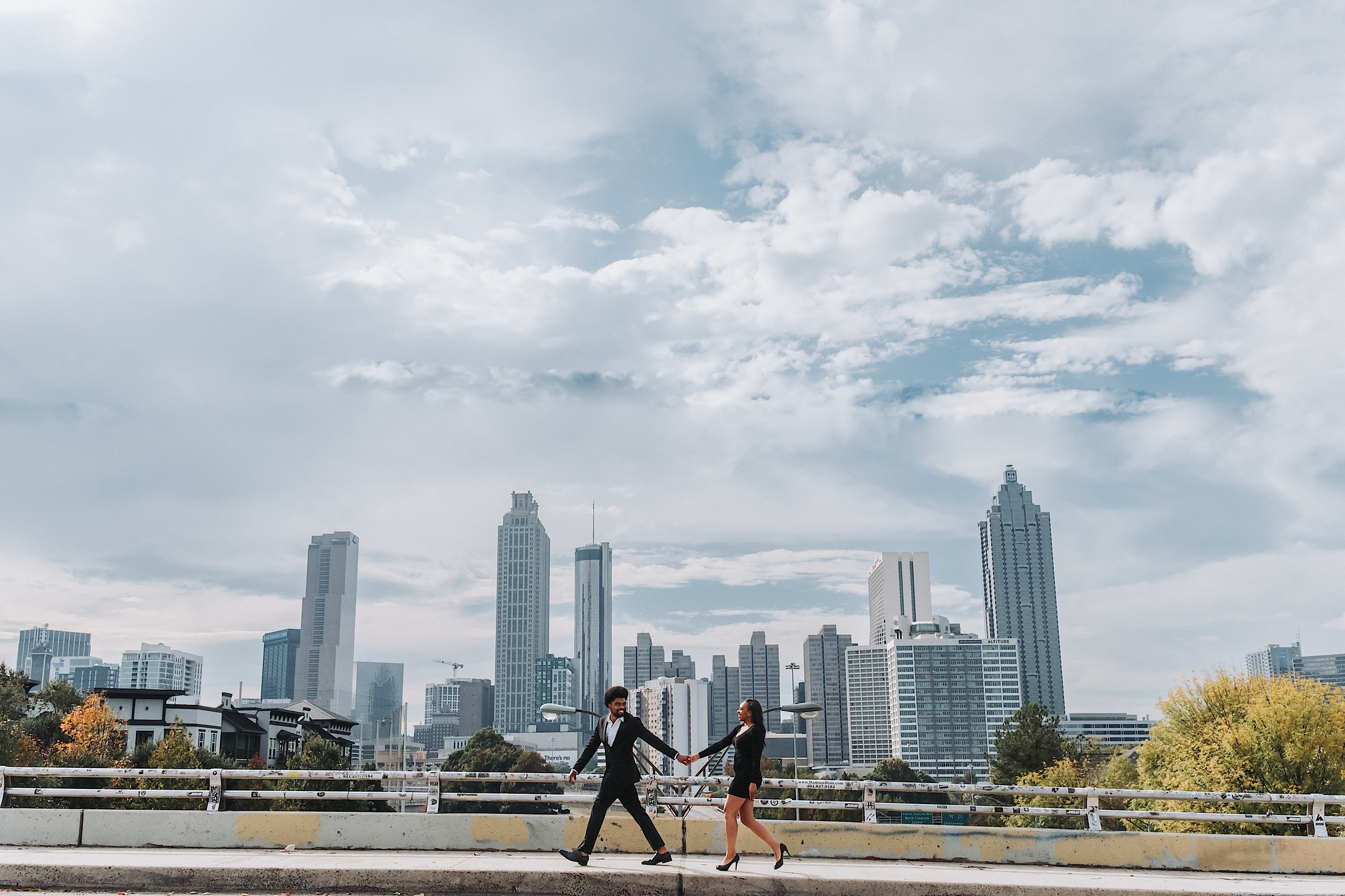 a couple walking together holding hands with the city skyline as their background