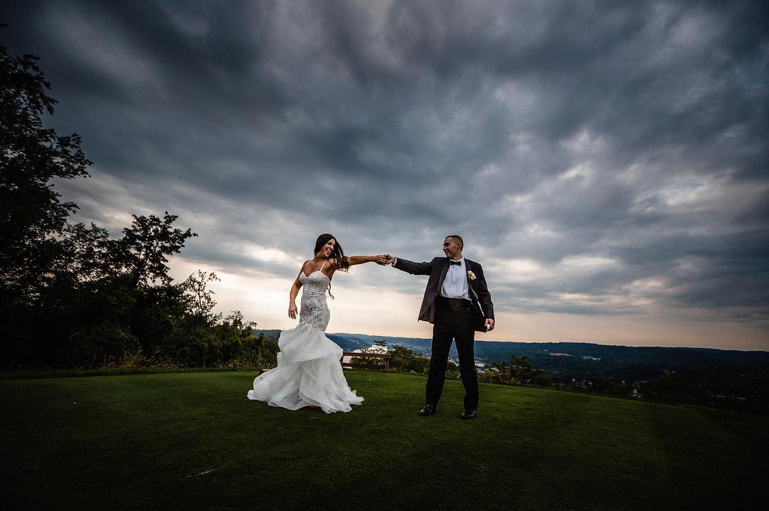 A bride and groom posing in a field