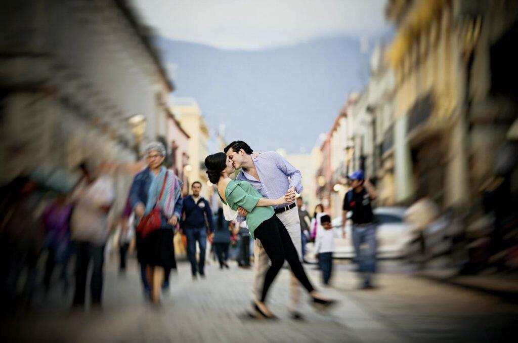 a couple kissing in the middle of a street while the surrounding is motion blurred