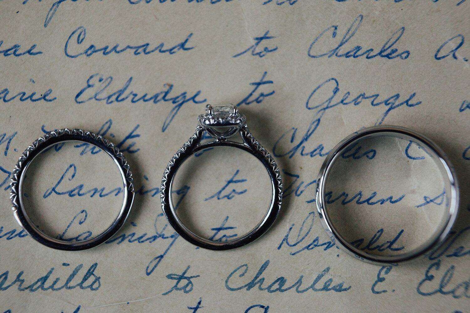 A set of 3 wedding rings placed on top of a handwritten letter