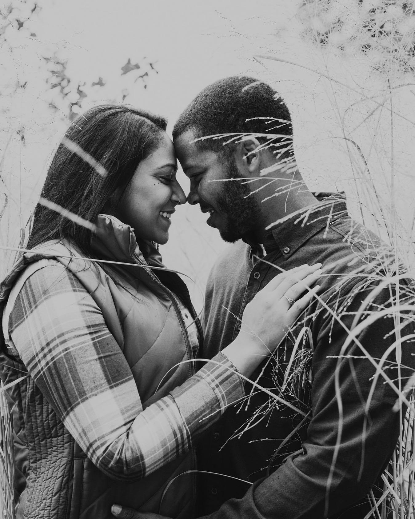 black and white photo of diverse couple nose to nose in a field of tall grass in the winter