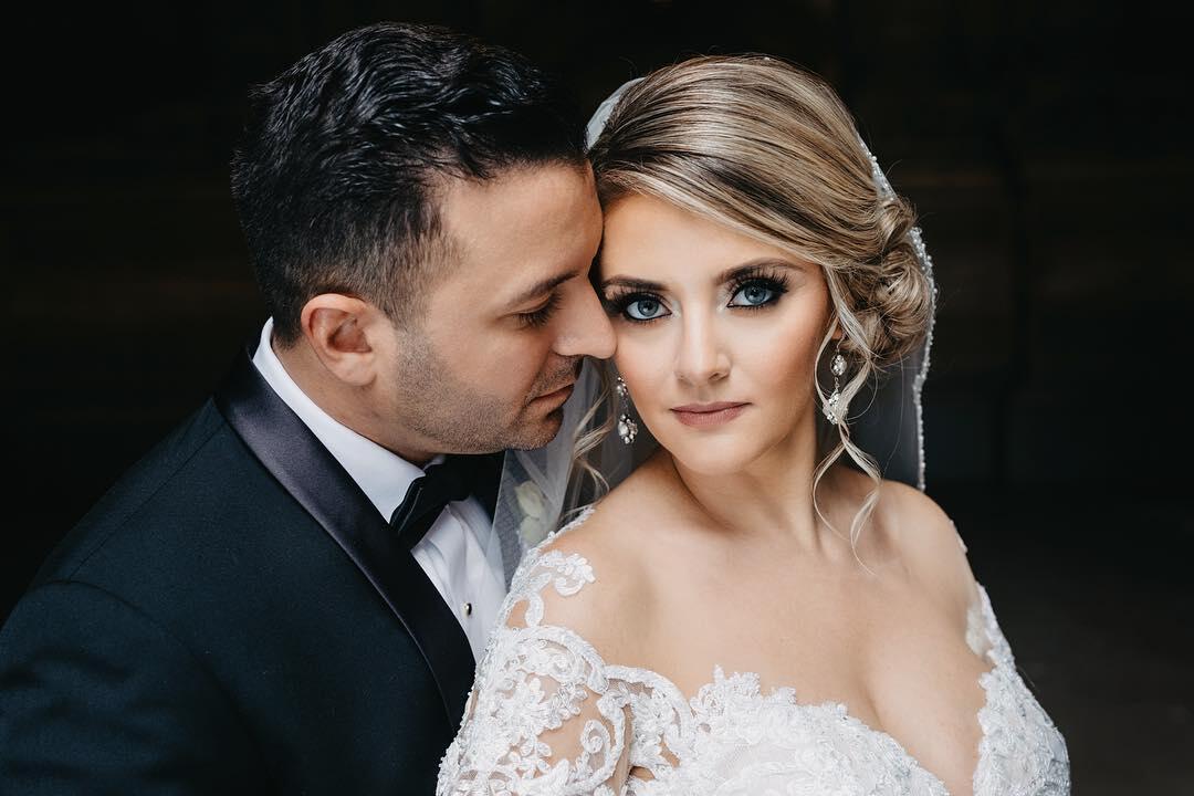 bride and groom close up with groom leaning into bride while bride looks directly at camera