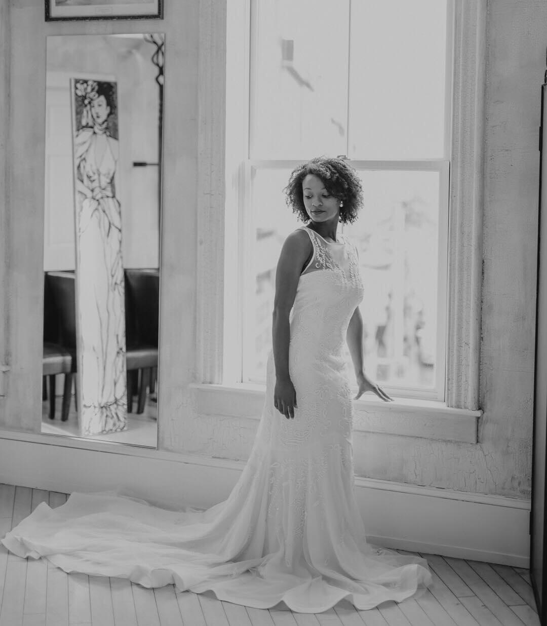 diverse black and white photo of woman in wedding dress posing by window 