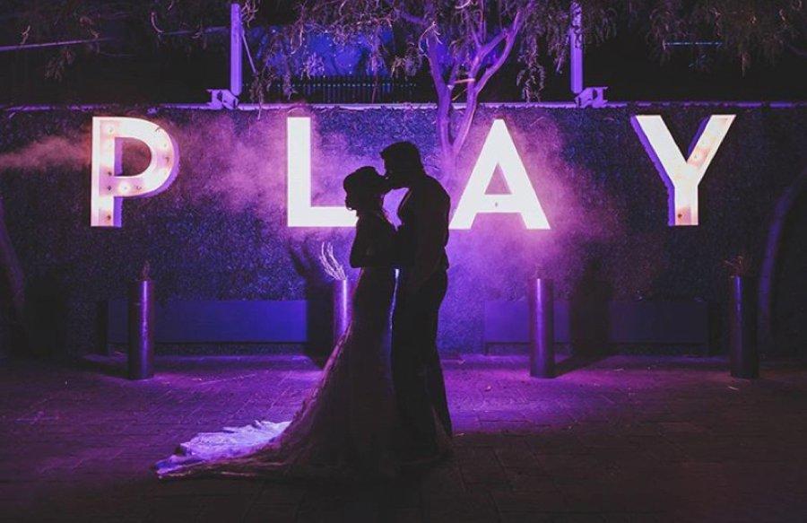 Silhouette of a couple posing in front of LED Letter Lights displaying - PLAY