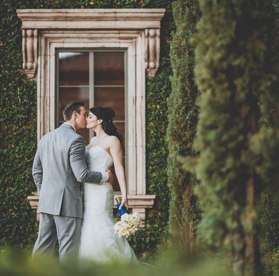 Bride and groom posing in front of a window